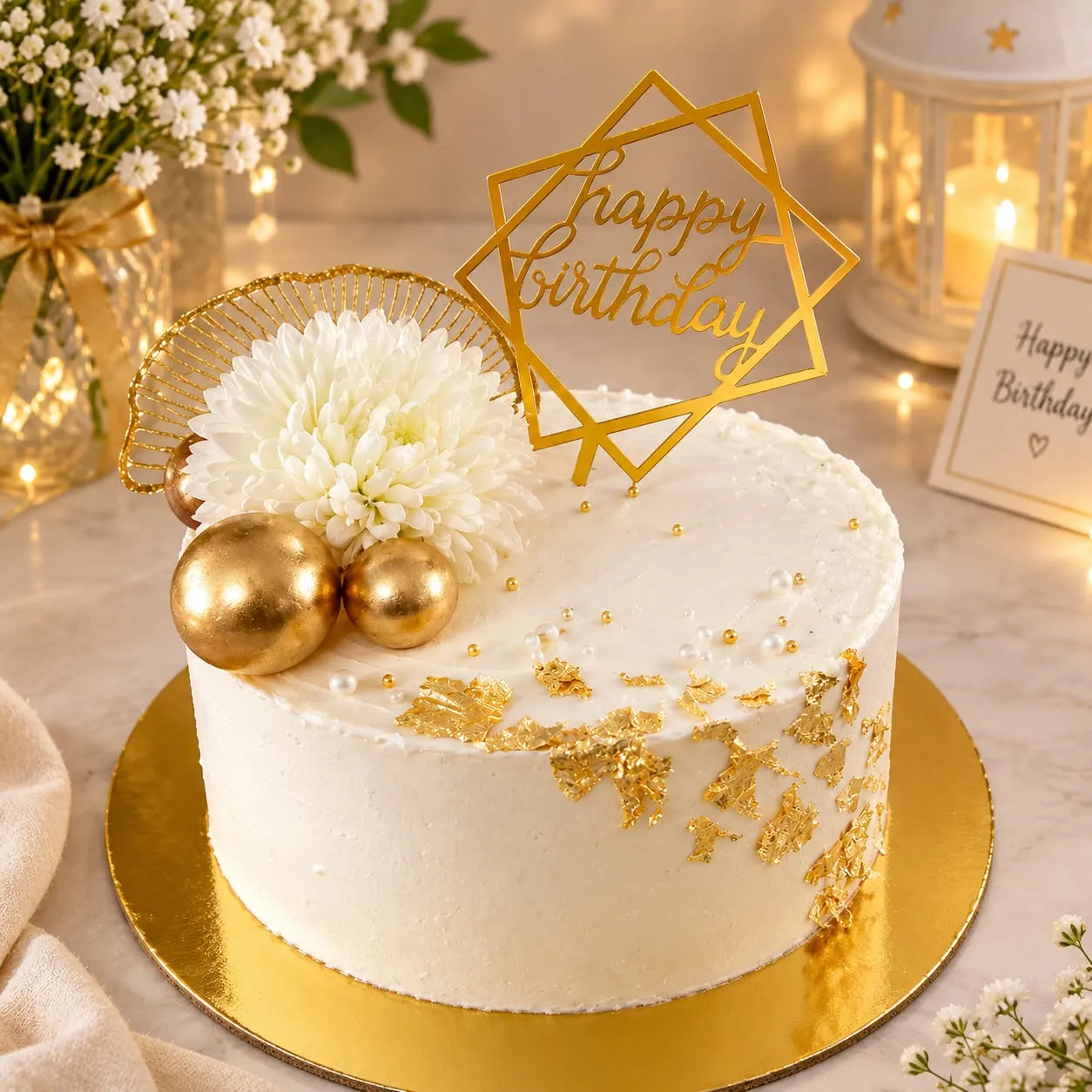 Elegant white birthday cake with gold detailing and a white flower
