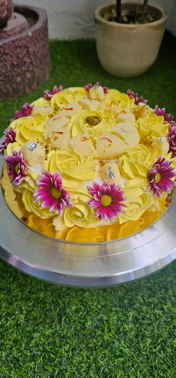Eggless Rasmalai cake finished with cream rosettes and flower accents