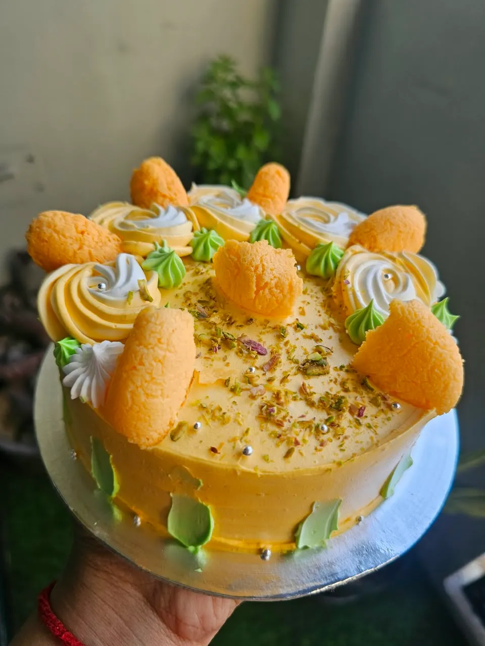 Golden-yellow Rasmalai-inspired cake with pistachios and cream swirls